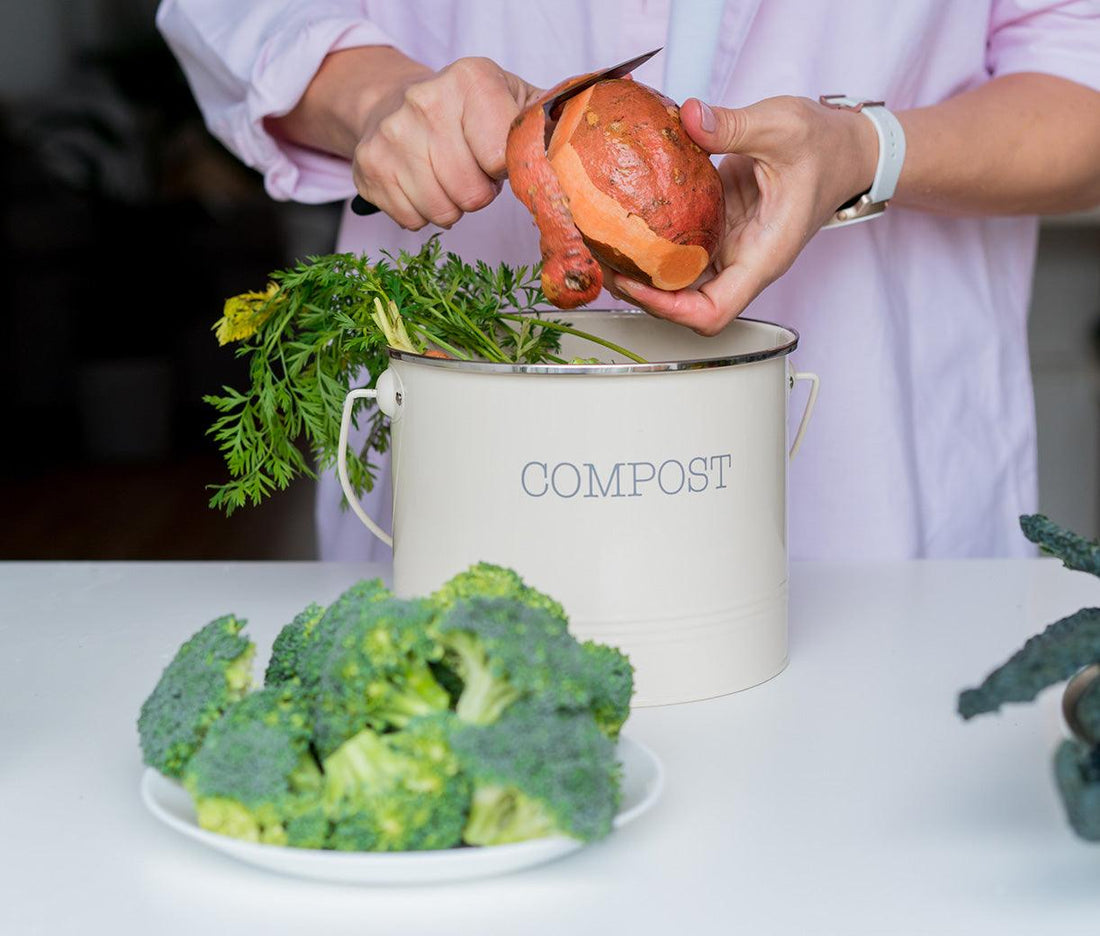 Food scraps being put into a compost bin on the kitchen bench